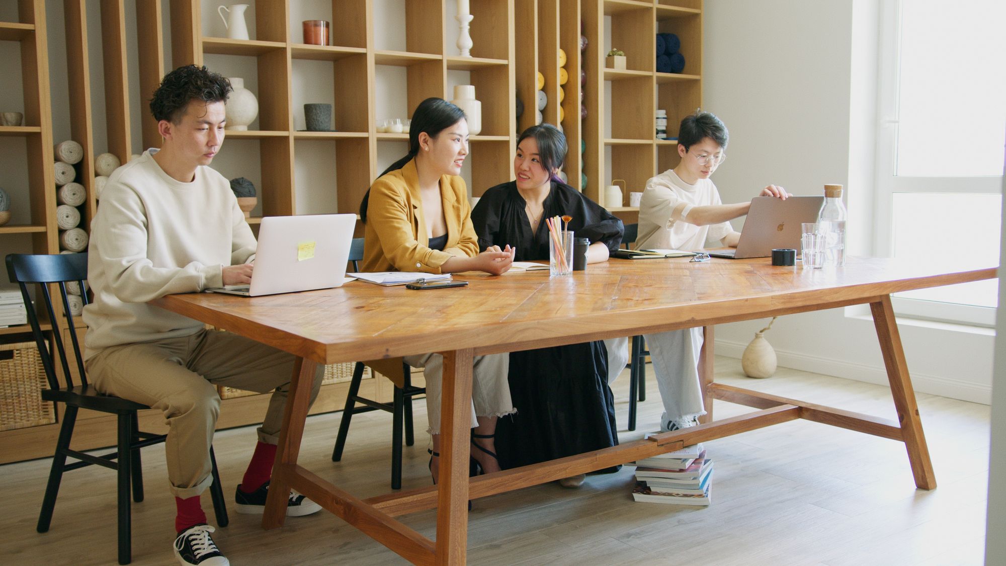 A small team working around one wooden table in warm window light