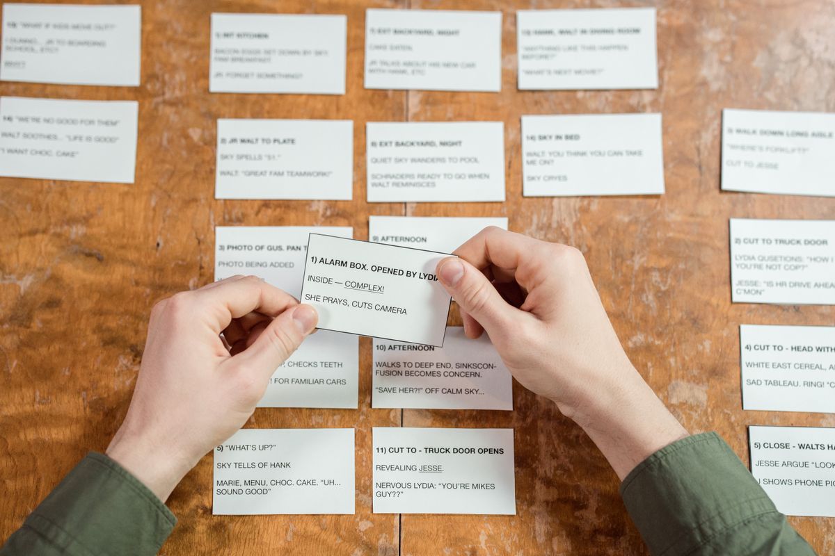 Hands sorting index cards laid out in rows on a wooden table
