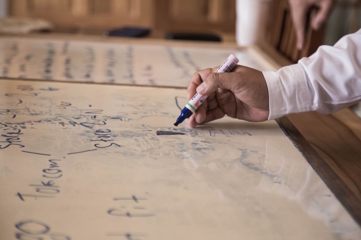 A hand writing with a marker on a large cream paper sheet