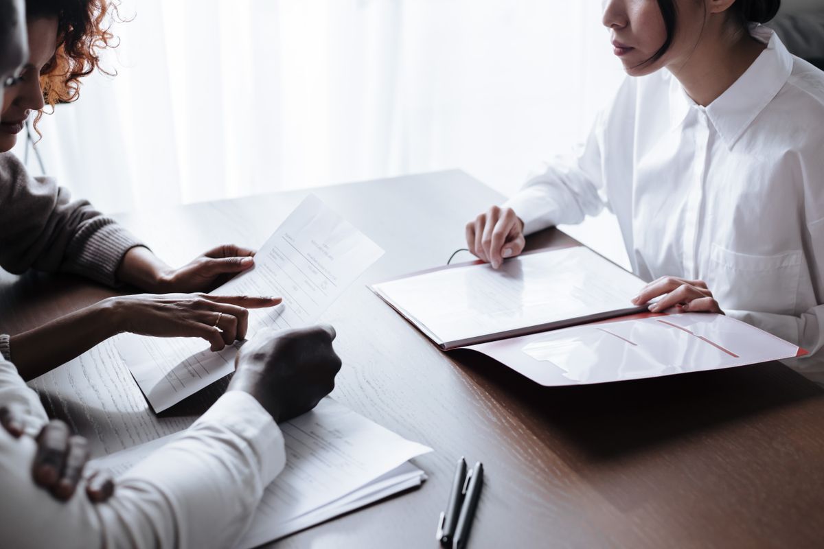 Documents passing between hands across a dark wooden table